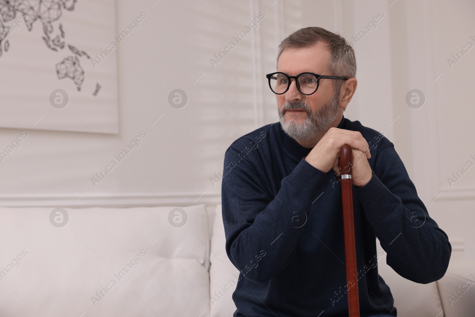 Photo of Mature man with walking cane at home. Space for text