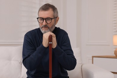 Photo of Mature man with walking cane at home