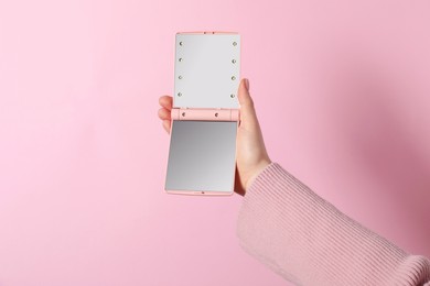 Photo of Woman holding pocket mirror on pink background, closeup