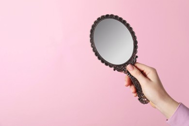 Photo of Woman holding vintage mirror on pink background, closeup. Space for text