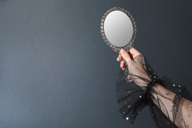 Photo of Woman holding vintage mirror on grey background, closeup. Space for text