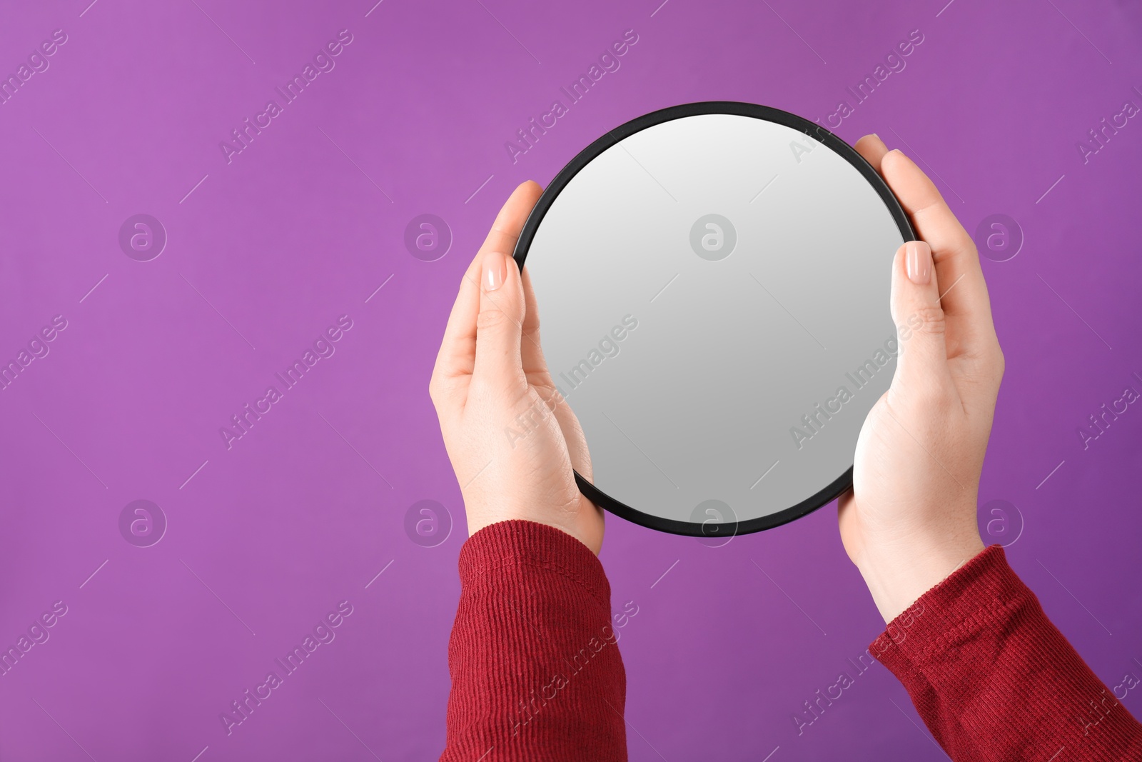 Photo of Woman holding round mirror on purple background, closeup. Space for text