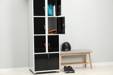 Photo of Lockers with personal belongings and bench in changing room at gym