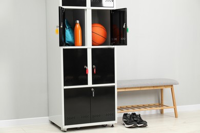 Photo of Lockers with personal belongings and bench in changing room at gym