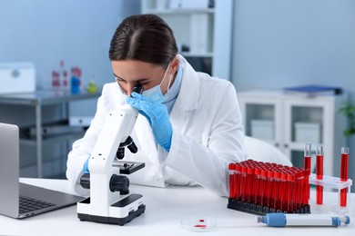 Photo of Laboratory testing. Doctor working with microscope at table indoors