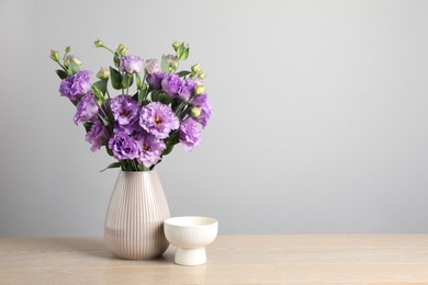 Photo of Vase with beautiful eustoma flowers on wooden table, space for text