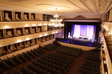 Photo of Theatre interior with stage, rows of comfortable seats and beautiful chandelier