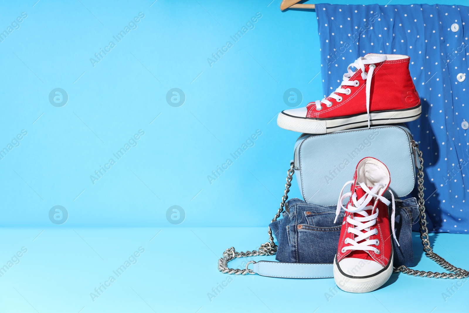 Photo of Clothes, shoes and bag on light blue background, space for text