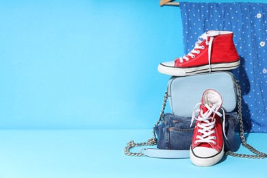 Photo of Clothes, shoes and bag on light blue background, space for text