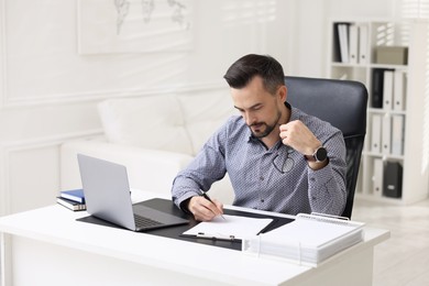 Photo of Handsome banker signing document at table in office