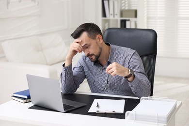 Photo of Tired banker working at table in office