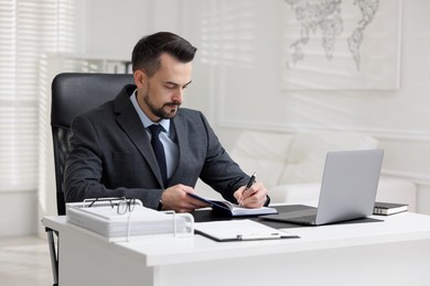 Handsome banker making notes at table in office