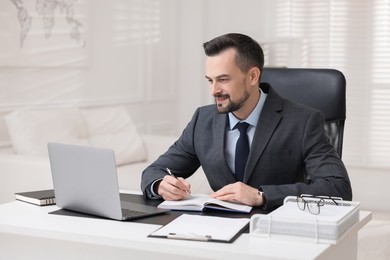 Photo of Handsome banker working at table in office