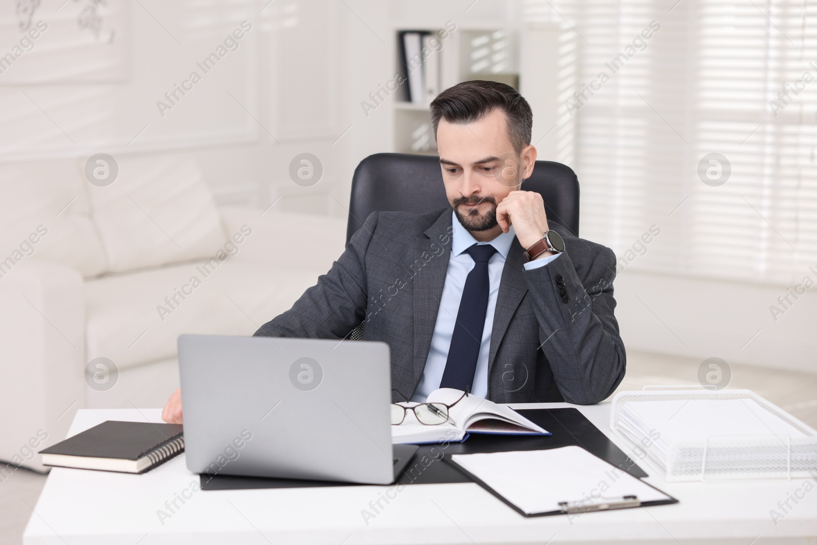 Photo of Handsome banker working with laptop at table in office