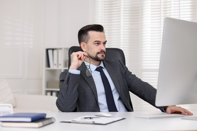 Photo of Handsome banker working with computer at table in office