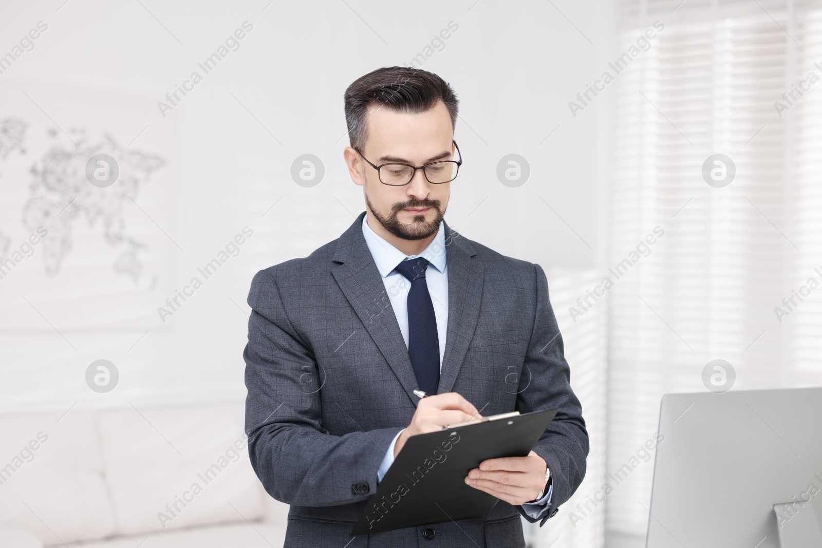 Photo of Handsome banker with clipboard making notes in office