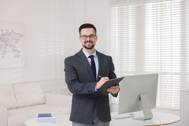 Photo of Smiling banker with clipboard making notes in office