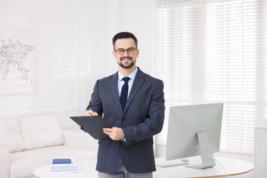 Photo of Smiling banker with clipboard making notes in office