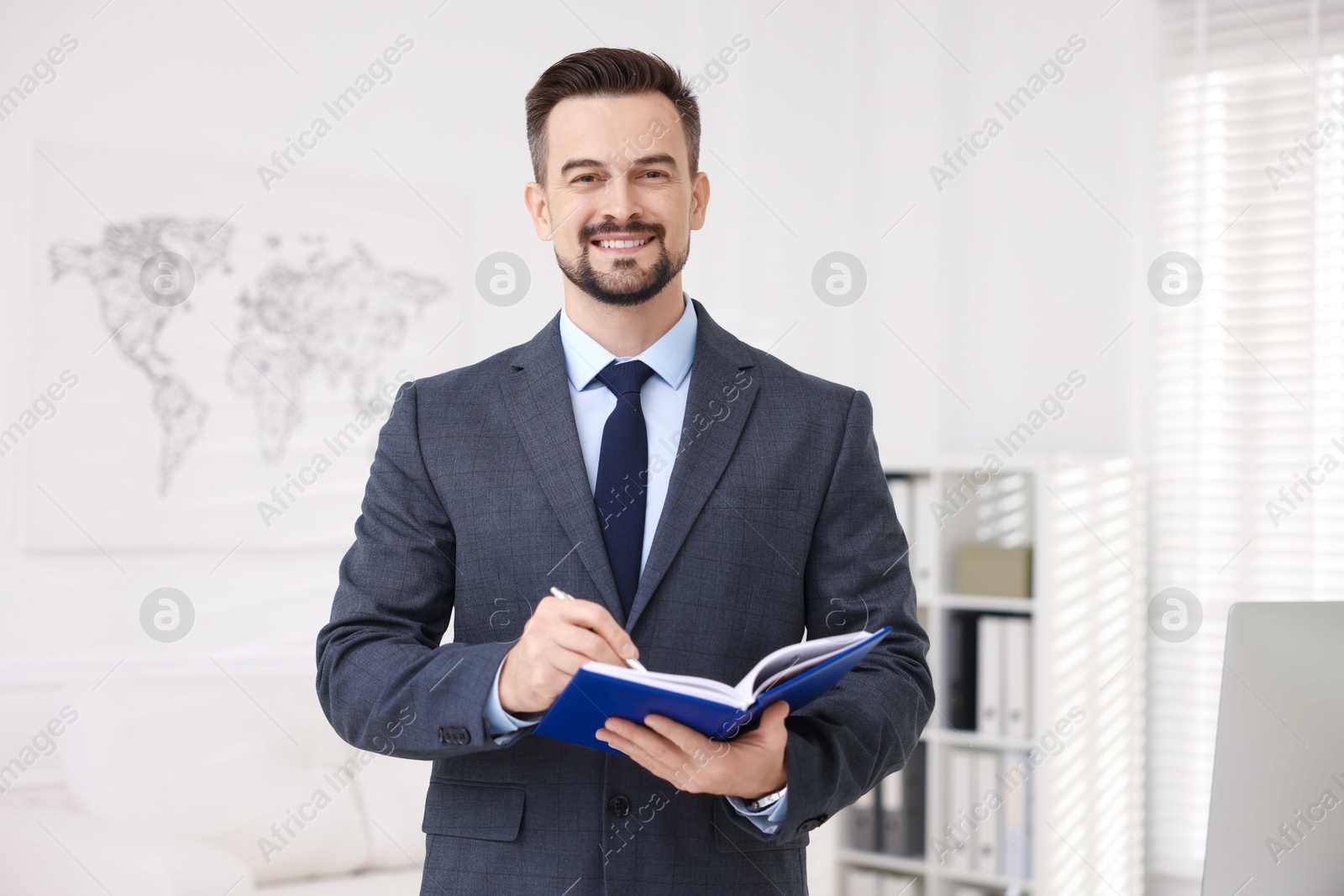 Photo of Smiling banker with notebook making notes in office