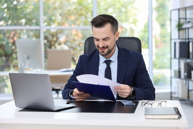 Photo of Handsome banker making notes at table in office