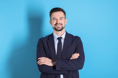 Photo of Portrait of smiling banker with crossed arms on light blue background