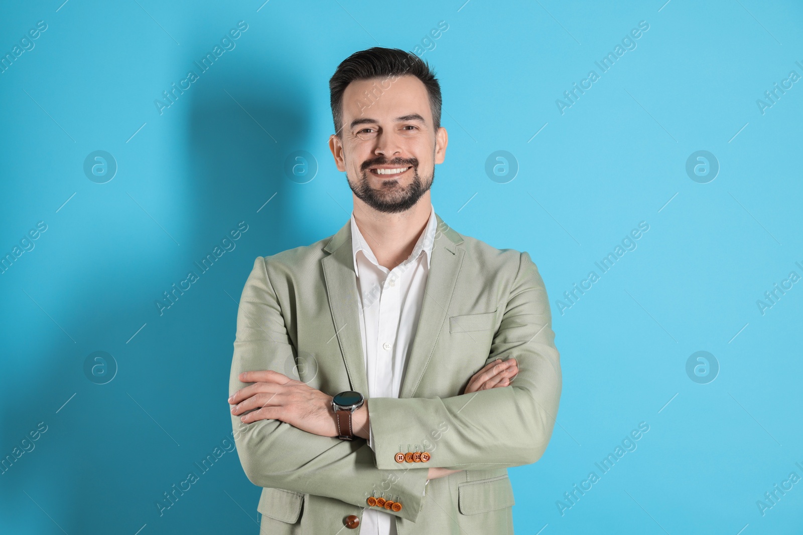 Photo of Portrait of smiling banker with crossed arms on light blue background