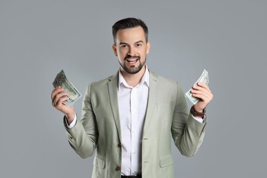 Photo of Portrait of excited banker with dollar banknotes on grey background