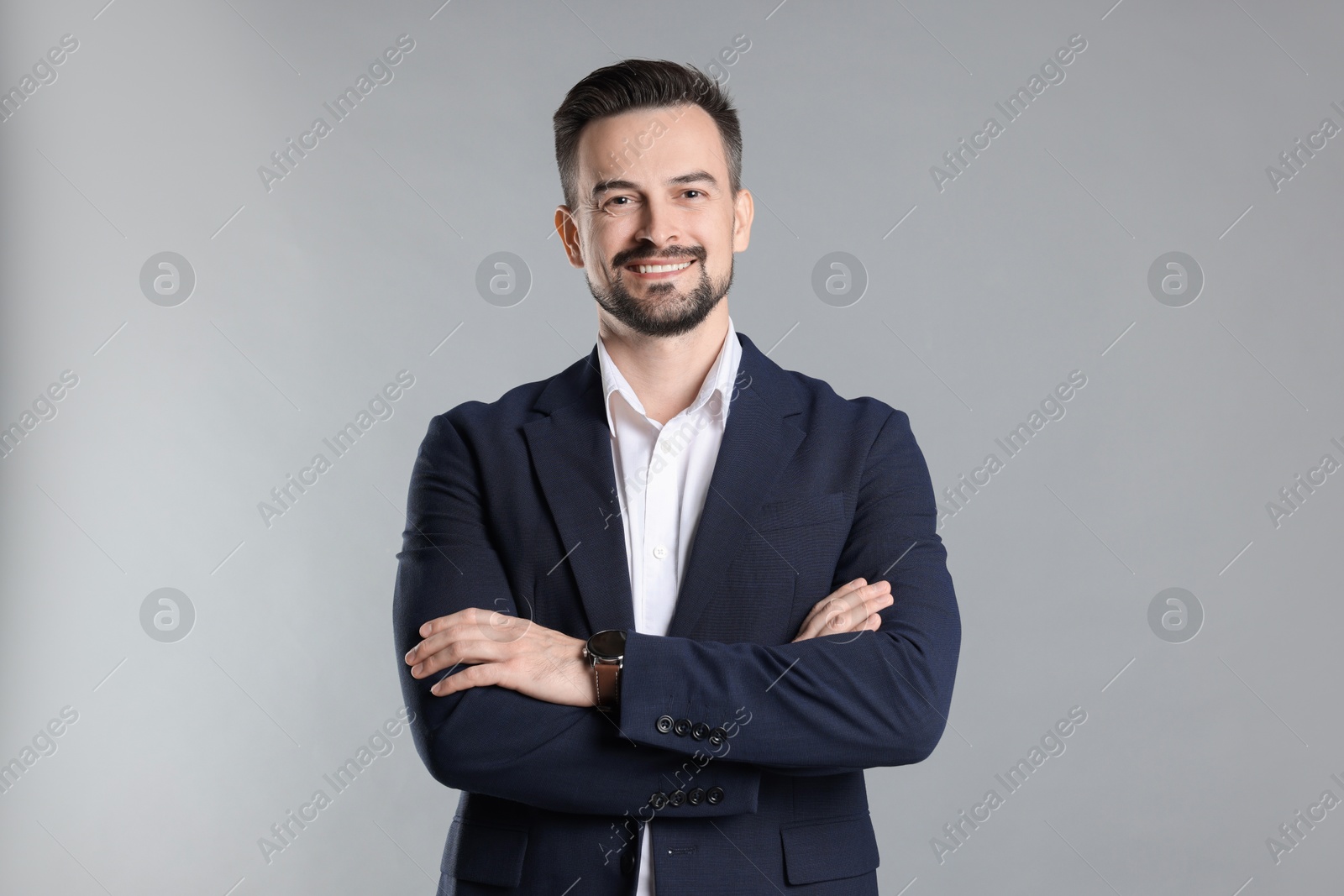 Photo of Portrait of smiling banker with crossed arms on grey background