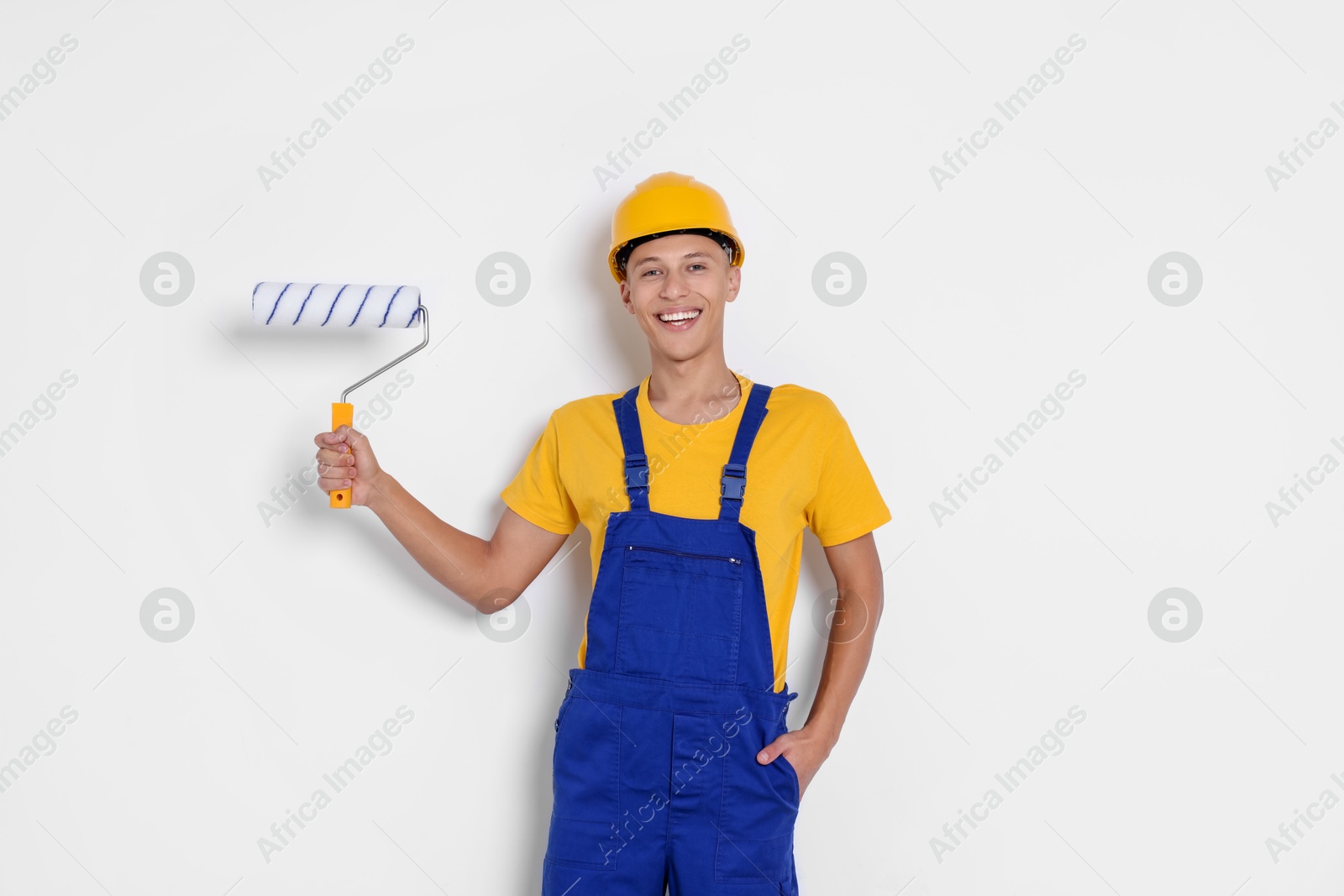 Photo of Portrait of young decorator with paint roller on white background