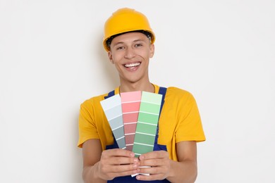 Photo of Portrait of young decorator with color palettes on white background