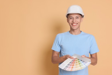 Photo of Portrait of young decorator with color palettes on beige background, space for text