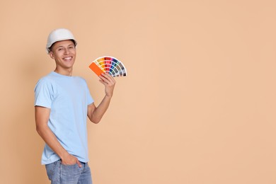 Photo of Portrait of young decorator with color palettes on beige background, space for text