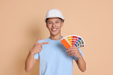 Photo of Portrait of young decorator with color palettes on beige background