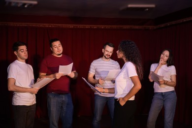 Photo of Professional actors with their scripts rehearsing in theatre