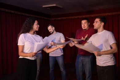 Photo of Professional actors with their scripts rehearsing in theatre