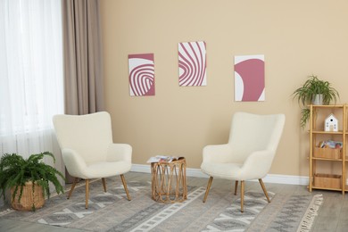 Photo of Soft armchairs and coffee table near beige wall indoors