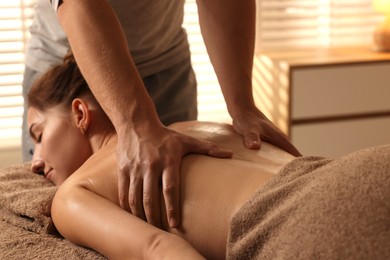 Photo of Osteopath massaging woman's back on couch indoors, closeup. Manual therapy