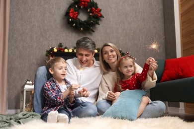 Photo of Lovely family with Christmas sparklers at home