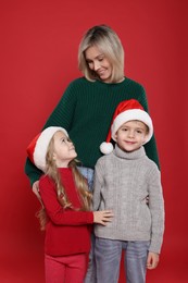 Photo of Mother and her little children on red background. Christmas season