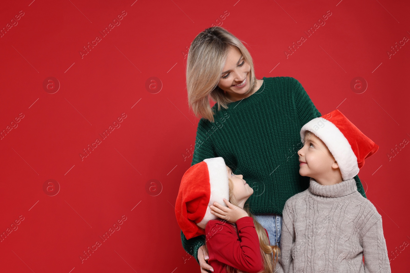 Photo of Mother and her little children on red background, space for text. Christmas season