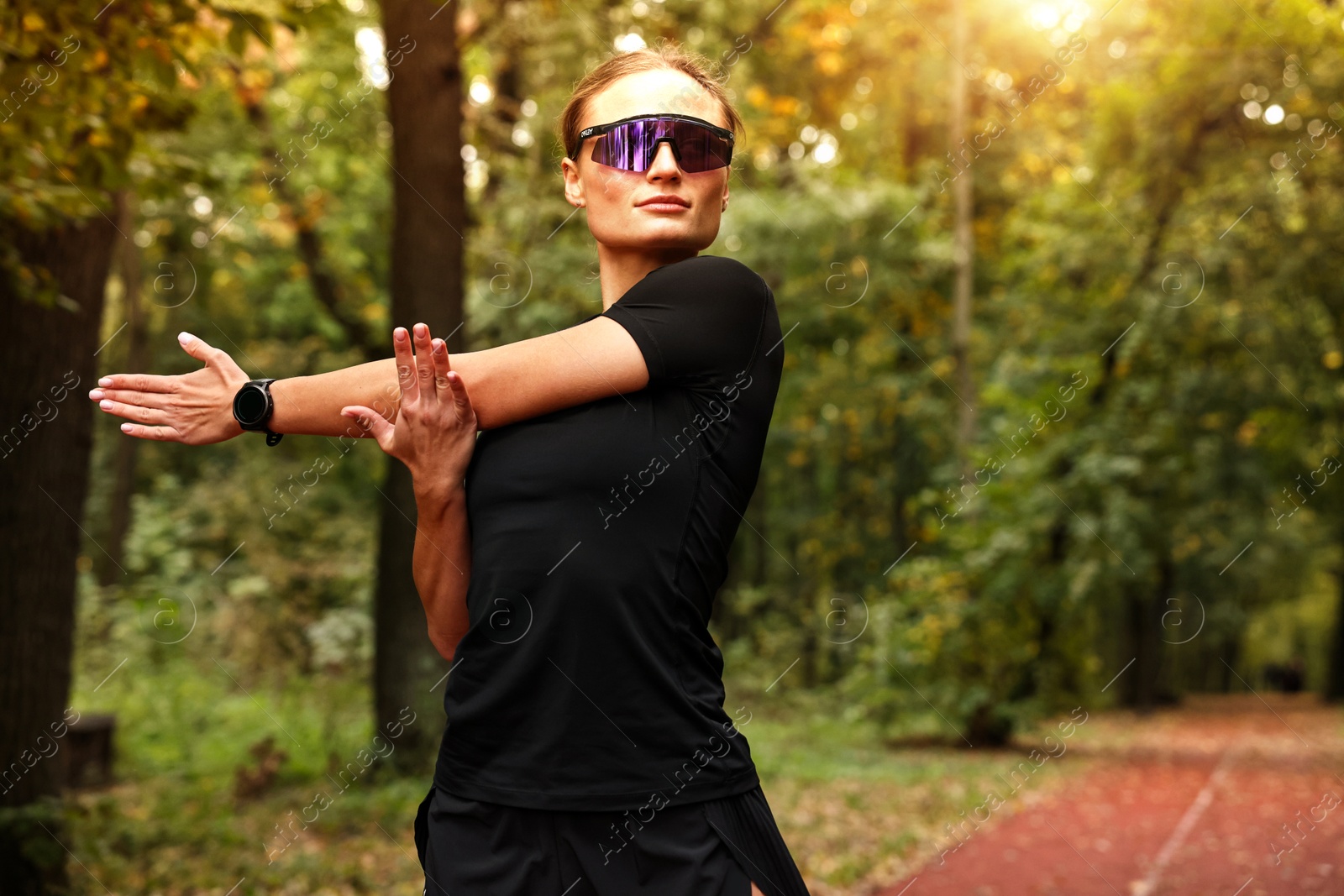 Photo of Young athletic woman stretching in park, space for text