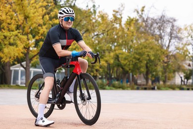 Photo of Athletic man with helmet and bicycle outdoors, space for text