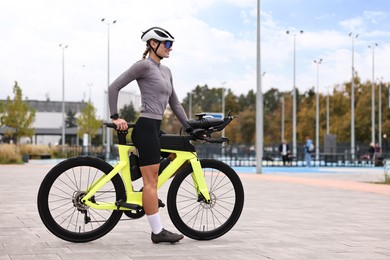 Photo of Young athletic woman with helmet and bicycle outdoors, space for text