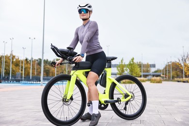 Photo of Young athletic woman with helmet and bicycle outdoors