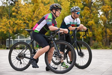 Photo of Athletic men with helmets and bicycles outdoors