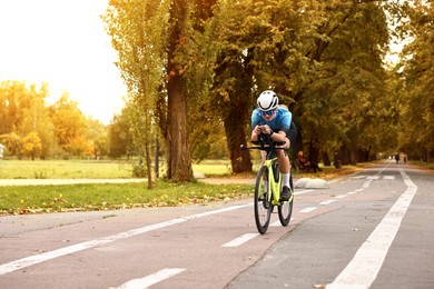 Photo of Athletic woman with helmet riding bicycle outdoors, space for text