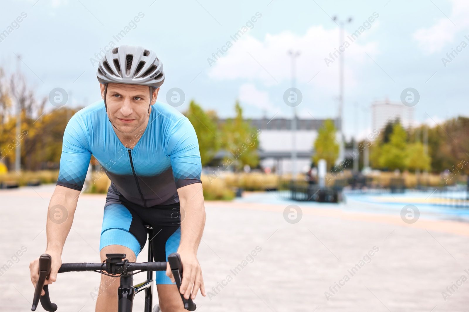 Photo of Athletic man with helmet riding bicycle outdoors, space for text