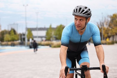 Photo of Athletic man with helmet riding bicycle outdoors, space for text