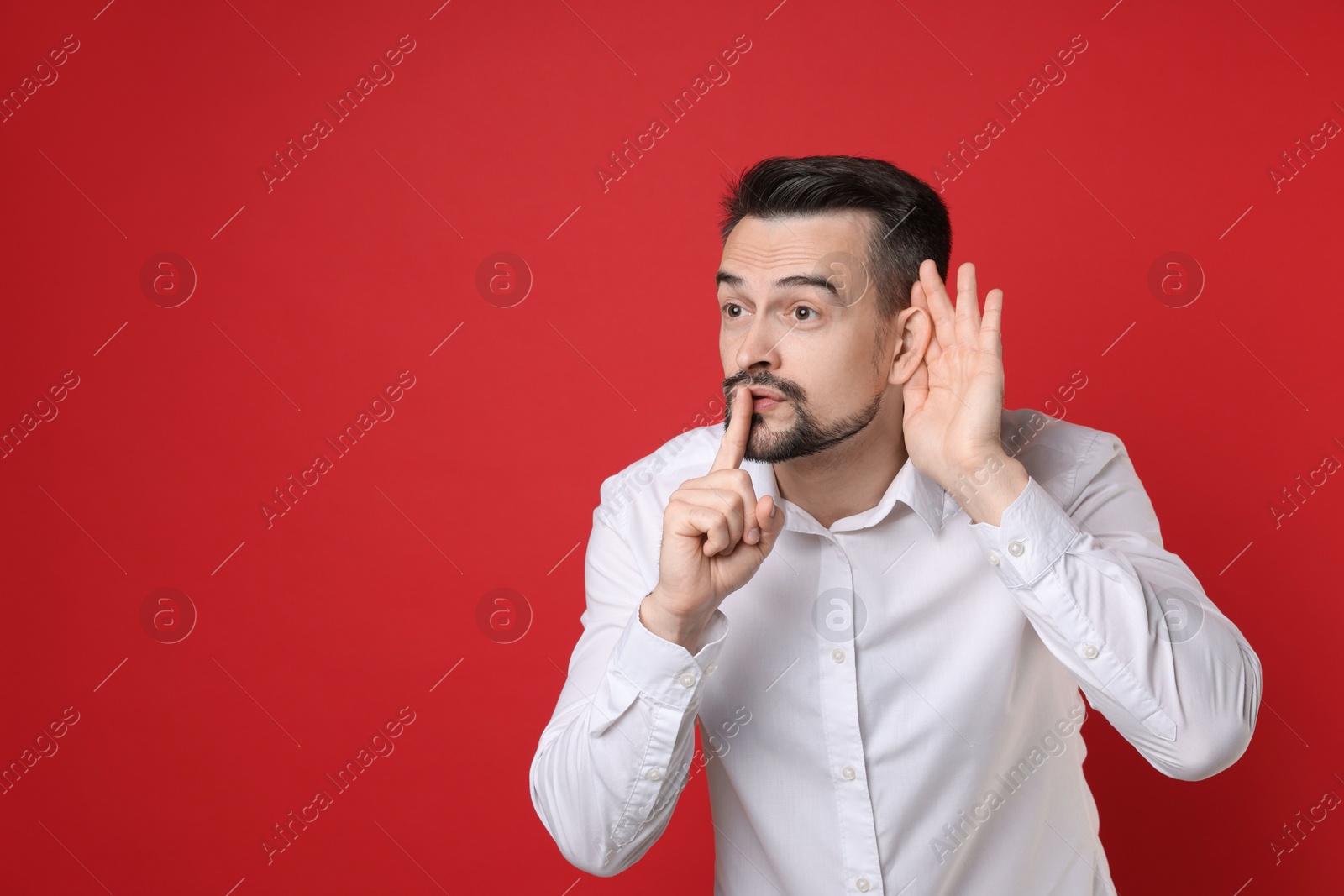 Photo of Man showing hand to ear gesture on red background, space for text