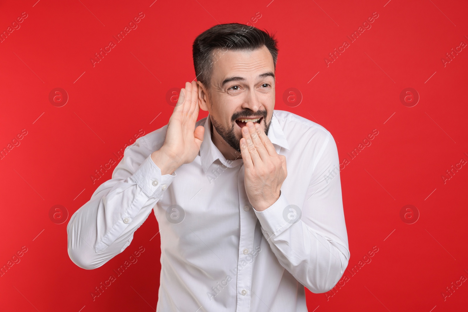 Photo of Man showing hand to ear gesture on red background